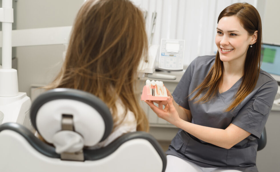 Dentist showing dental implants model to patient.