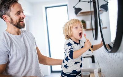 Mature father with small son indoors in bathroom, brushing teeth.