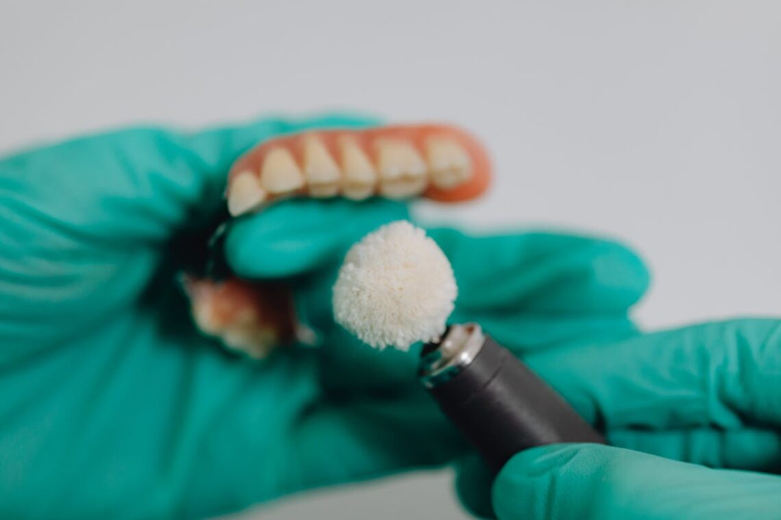 A Close-Up Shot of a Dentist hand Polishing Dentures
