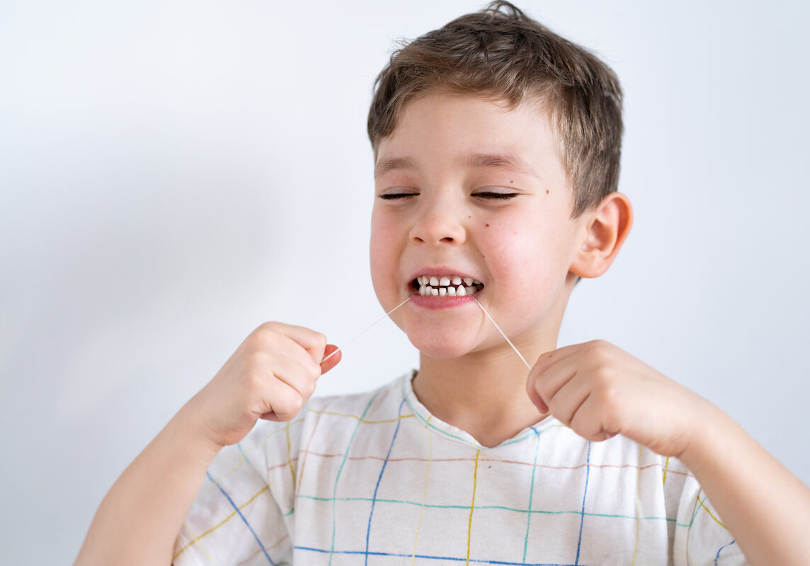 dark haired boy using a dental floss
