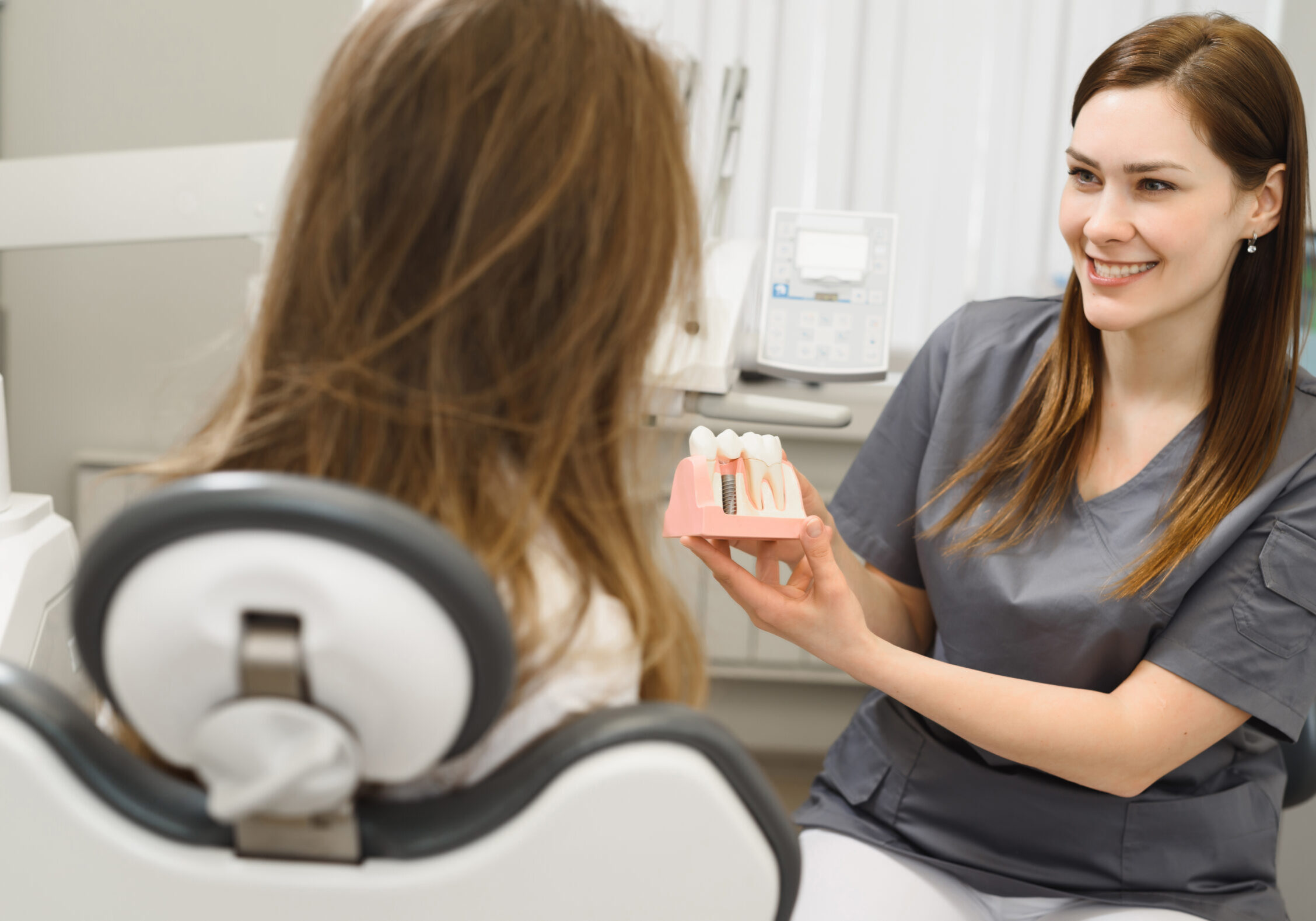 Dentist showing dental implants model to patient.