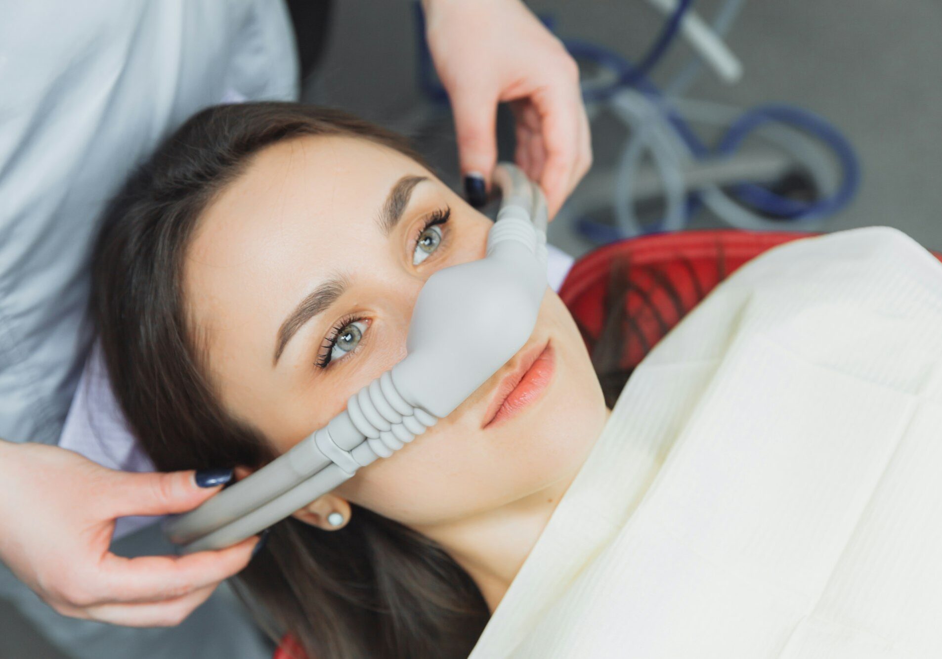 dentist puts inhalation sedative mask on his patient.