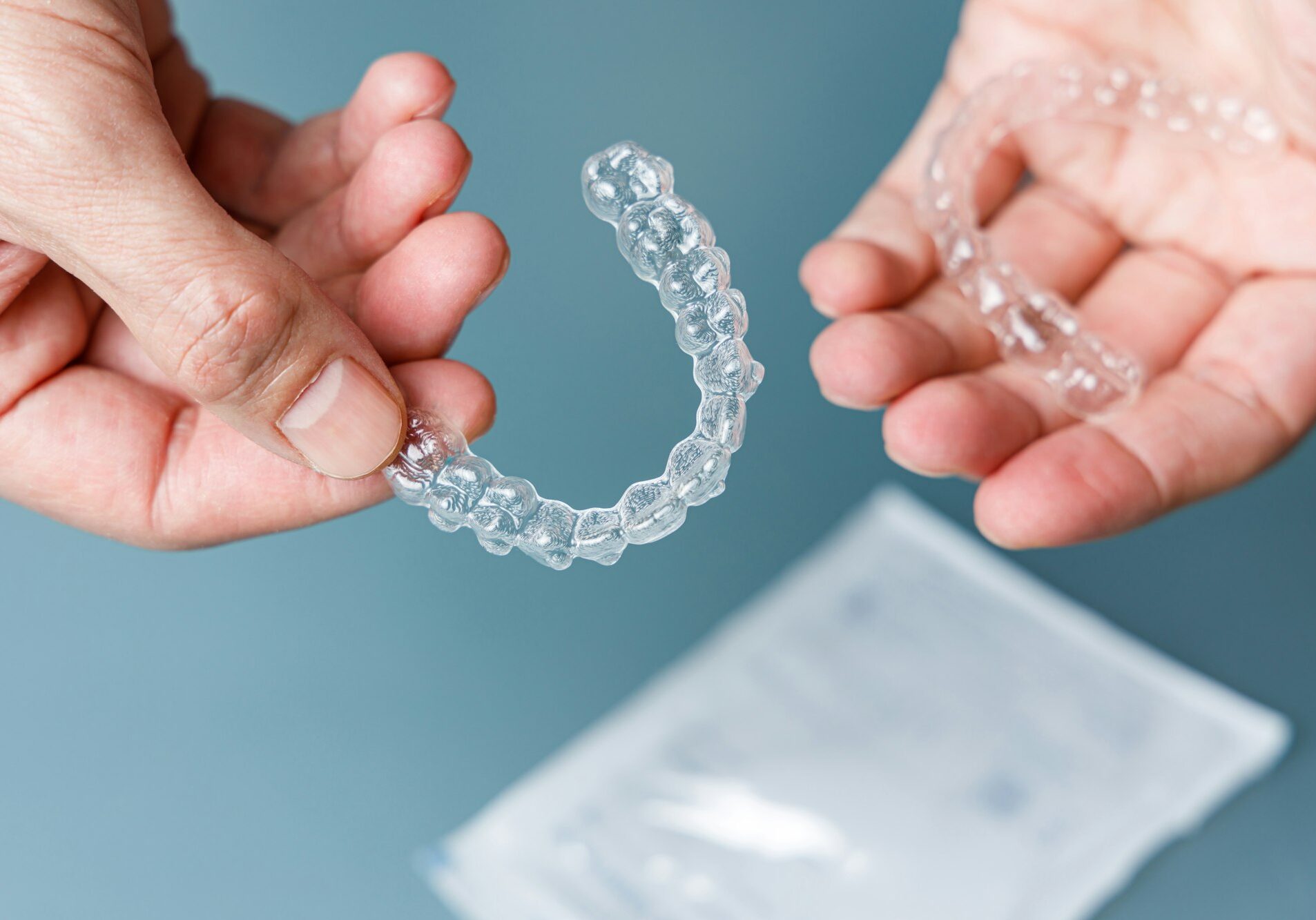 Hands holding transparent aligners. Invisalign orthodontics concept