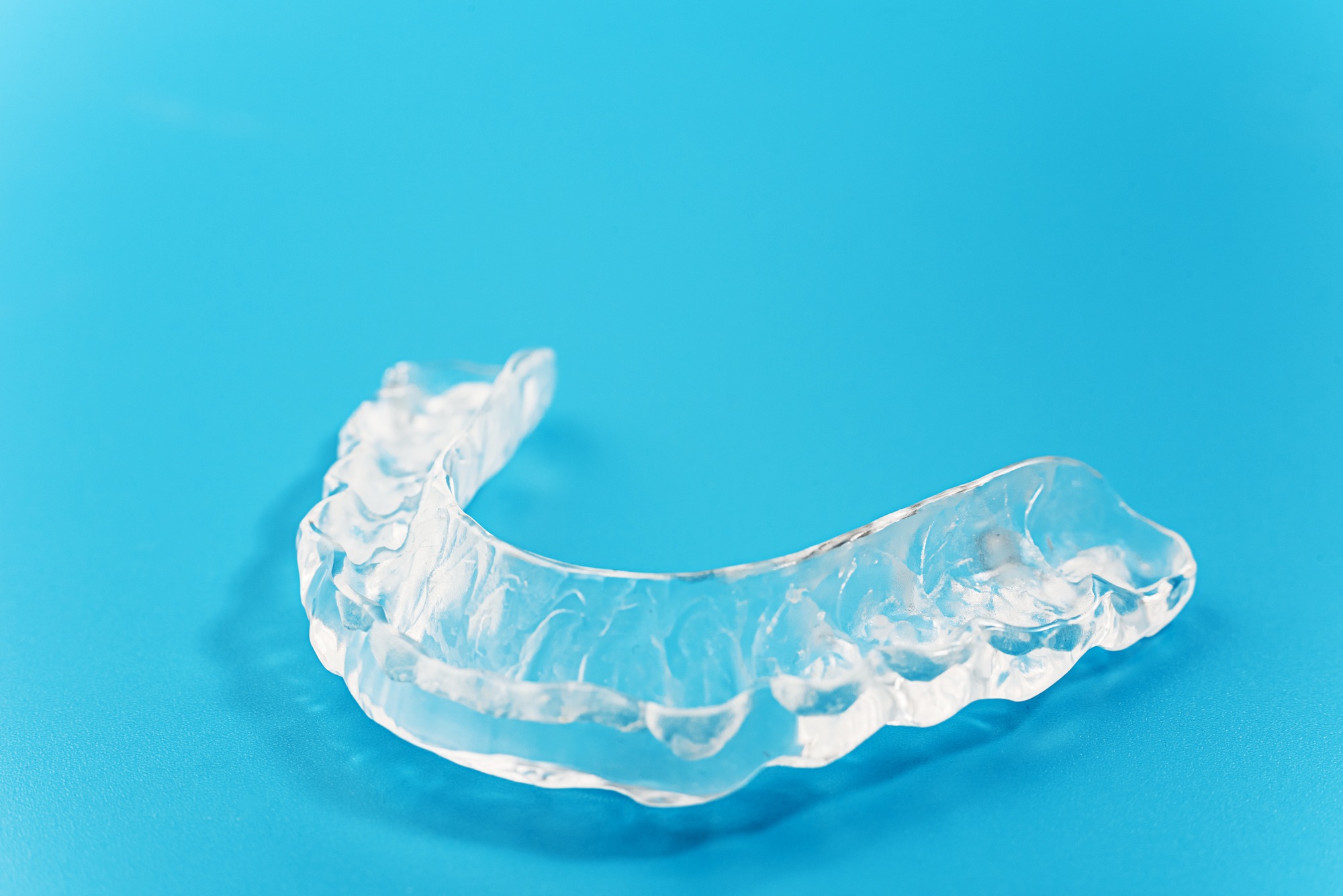 Clear dental retainer on blue background.