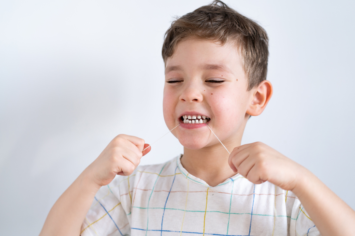 dark haired boy using a dental floss