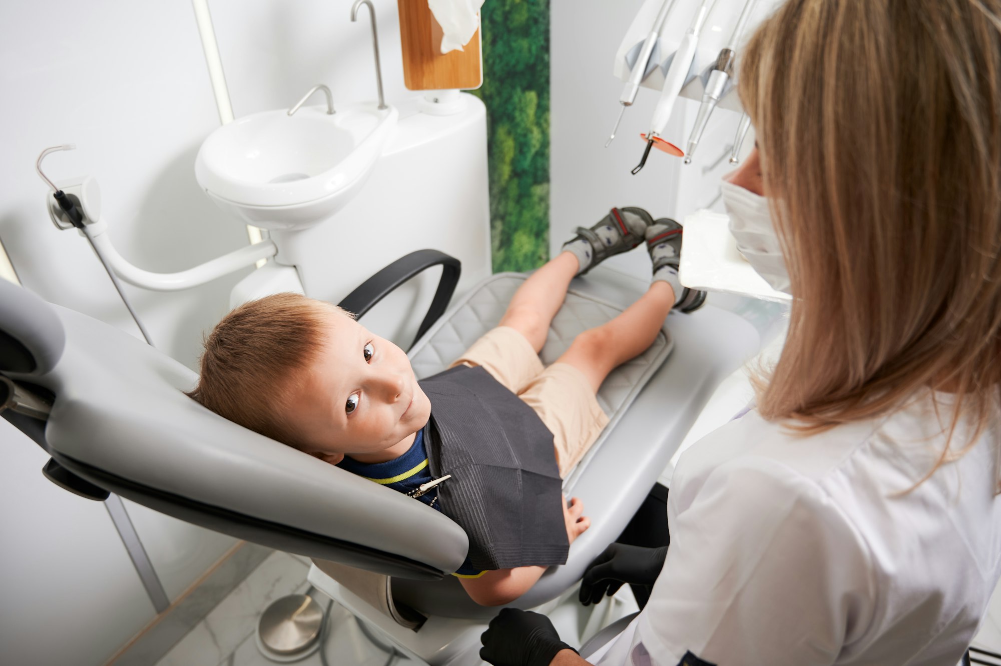 Cute child sitting in dental chair in dental office.
