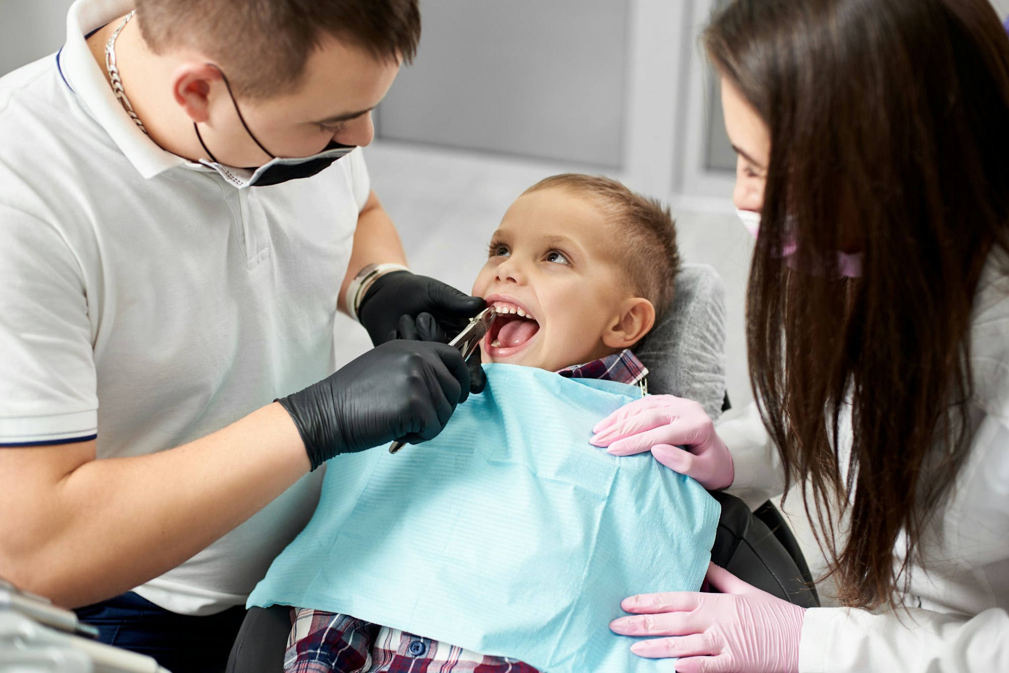 Child receiving dental checkup from two dentists.