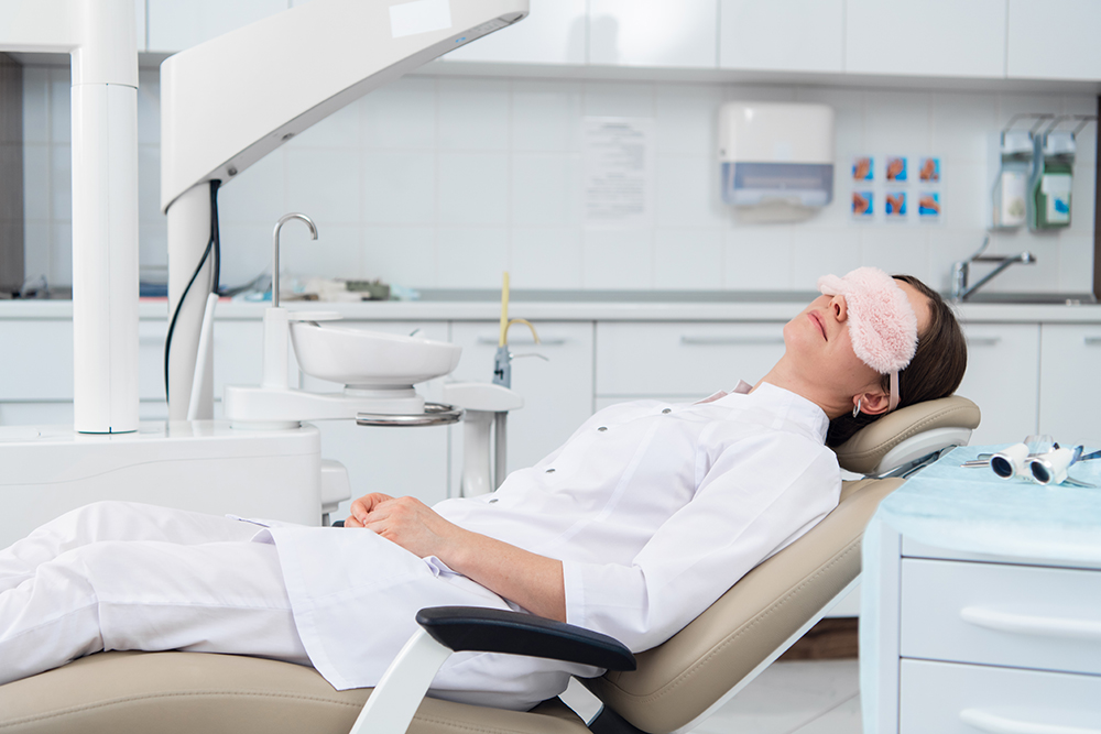 Patient relaxing at dental clinic with eye mask.