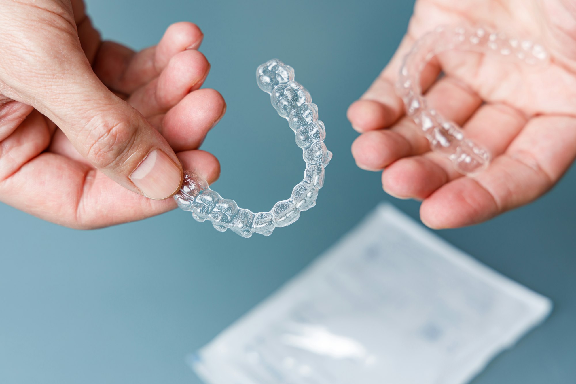 Hands holding clear dental aligners.