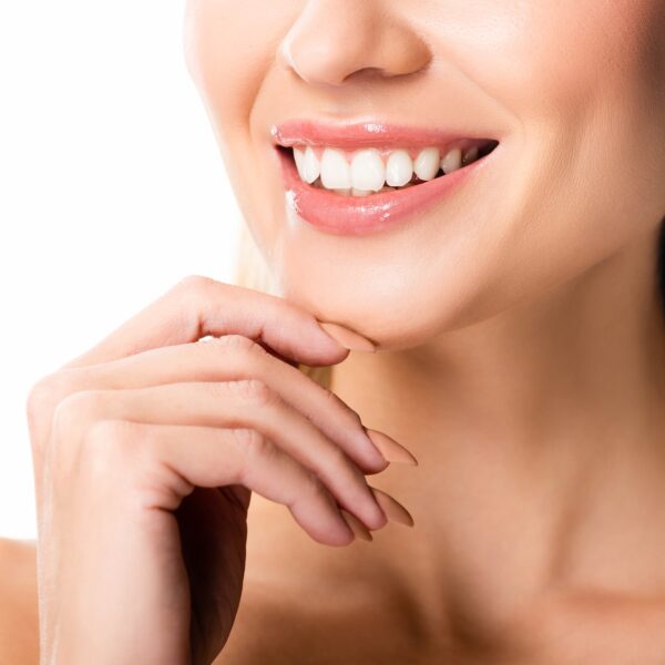 Smiling woman with perfect teeth and hand on chin.