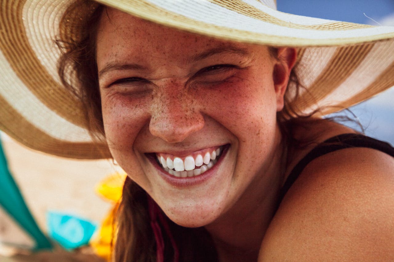 Smiling person wearing a sun hat at beach.