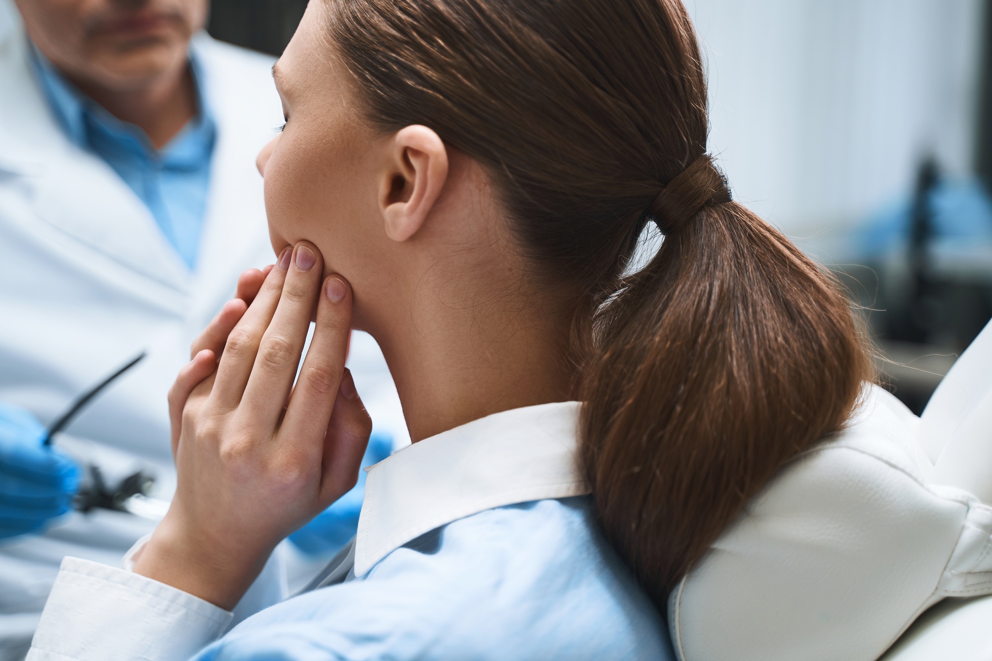 Woman holding jaw, consulting dentist.